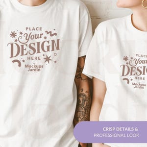 May include: Two white t-shirts with a brown design that says "PLACE Your DESIGN HERE* Mockups Jardin".