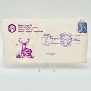 May include: A white envelope featuring a purple printed graphic of an elk, text reading Denver Lodge No. 17, 2475 West 26th Avenue, Denver, CO 80211, Mother Lodge of The Rockies, a purple postmark dated July 13, 1986, and a 22-cent Liberty postage stamp.