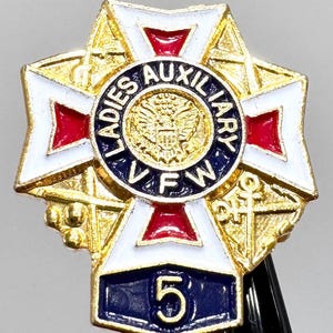 Puede incluir: Un pin dorado con un dise&ntilde;o de cruz, con detalles de esmalte blanco, rojo y azul. El c&iacute;rculo central dice "Ladies Auxiliary VFW" alrededor de un emblema dorado. Una pancarta azul en la parte inferior muestra el n&uacute;mero "5".