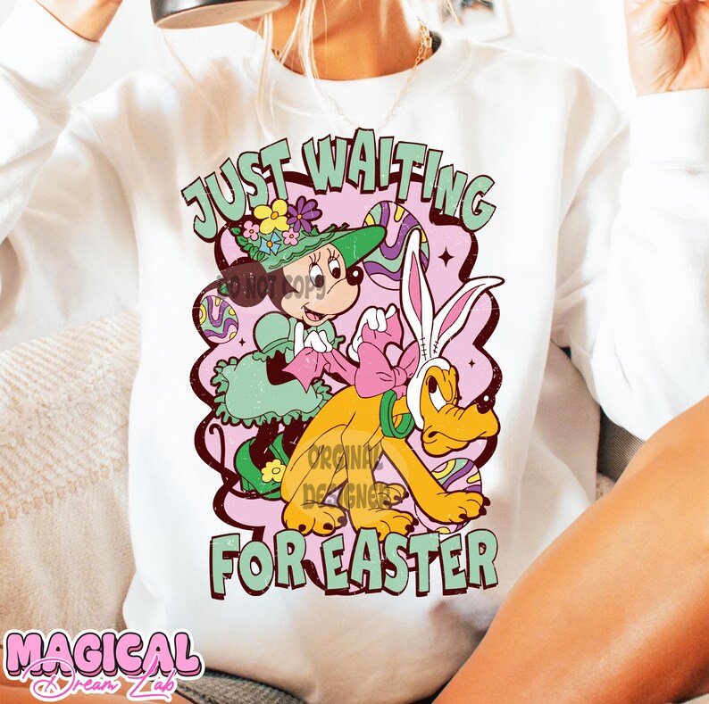 Puede incluir: Sudadera blanca con un estampado gr&aacute;fico de Mickey Mouse y Pluto vestidos con atuendos de Pascua. El texto "Just Waiting For Easter" est&aacute; impreso en la sudadera.