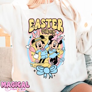 May include: White sweatshirt with a colorful graphic of Mickey Mouse and Minnie Mouse dressed in Easter outfits. The graphic includes the text "Easter vibes".