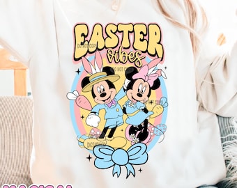 Puede incluir: Sudadera blanca con un gráfico colorido de Mickey Mouse y Minnie Mouse vestidos con atuendos de Pascua. El gráfico incluye el texto "Easter vibes".
