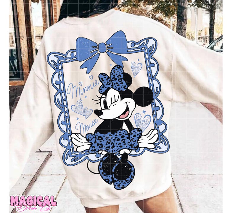 May include: Cream-colored sweatshirt featuring a Minnie Mouse graphic. The design includes a blue bow, a framed image of Minnie, and the words "Minnie Mouse." The graphic has a distressed, vintage look.