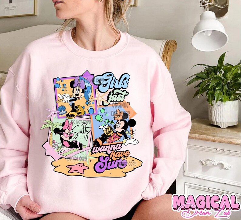 May include: Pink sweatshirt with a graphic print of Mickey Mouse and Minnie Mouse characters. The text on the graphic says "Girls just wanna have sun".