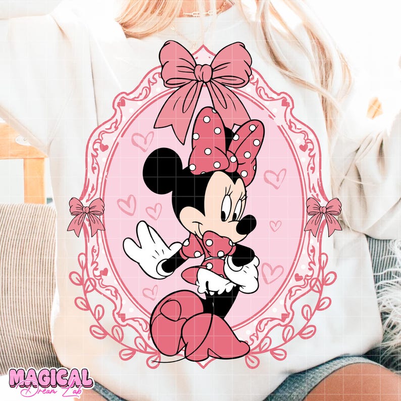 May include: A white sweatshirt featuring a pink Minnie Mouse graphic. The graphic includes Minnie Mouse in a pink polka-dot dress and bow, set within a pink oval frame with hearts and bows. The words "MAGICAL DREAM LAB" are at the bottom.