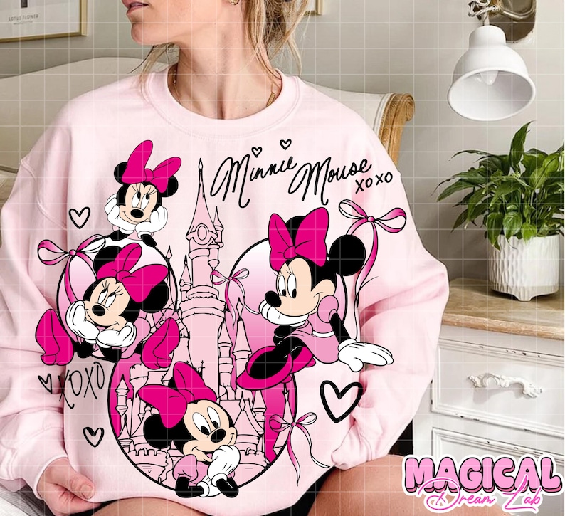 May include: A light pink sweatshirt featuring Minnie Mouse in a circular design with a castle and hearts. The words "Minnie Mouse xoxo" are written in cursive. The sweatshirt has a cartoon graphic of Minnie Mouse in pink.