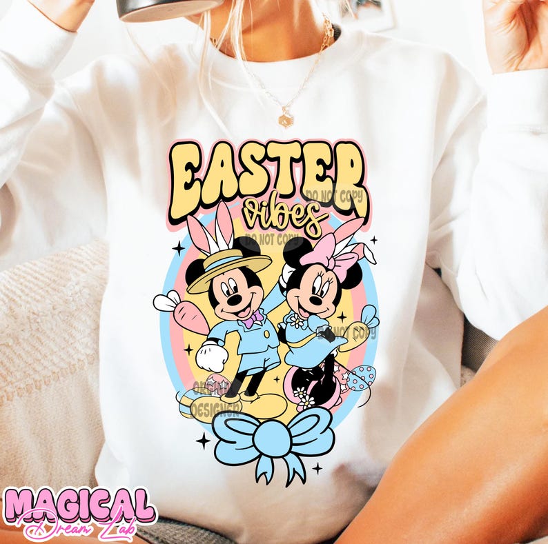 May include: White sweatshirt with a colorful Easter design featuring Mickey and Minnie Mouse in pastel colors. The text "Easter Vibes" is written in a retro font.