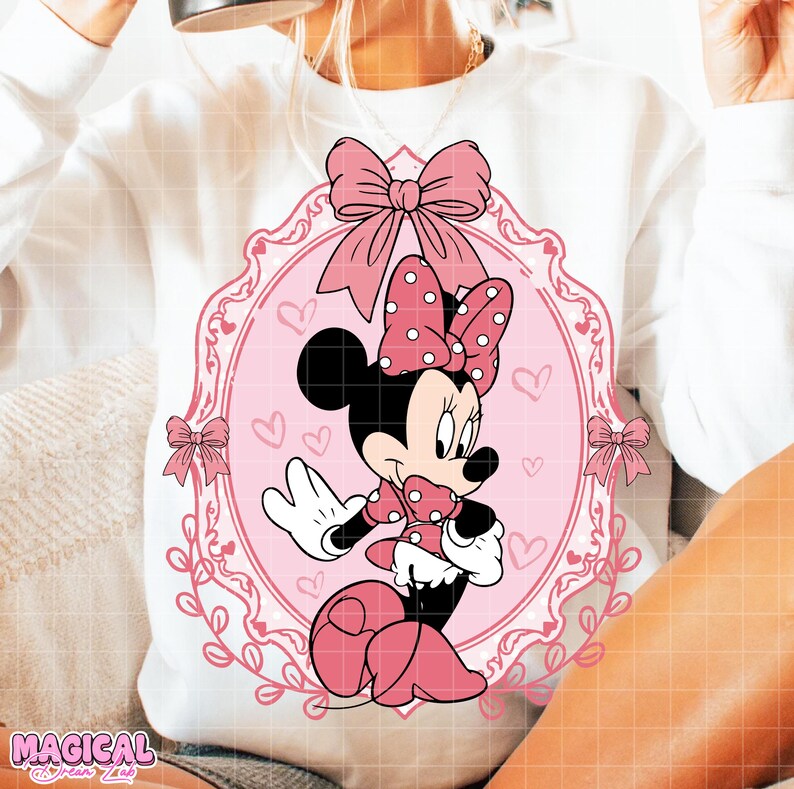 May include: White sweatshirt featuring a pink Minnie Mouse graphic. The graphic includes a pink bow with white polka dots, a pink frame, and pink bows. The words "MAGICAL DREAM LAB" are at the bottom left.