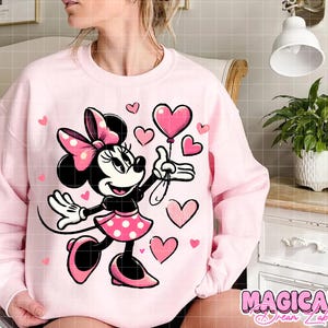 Puede incluir: Sudadera rosa claro con un dise&ntilde;o de Minnie Mouse sosteniendo un globo en forma de coraz&oacute;n. Minnie Mouse lleva una falda y un lazo de lunares rosas. Hay corazones rosas dispersos alrededor del dise&ntilde;o. El texto "MAGICAL Dream Lab" est&aacute; en la parte inferior.