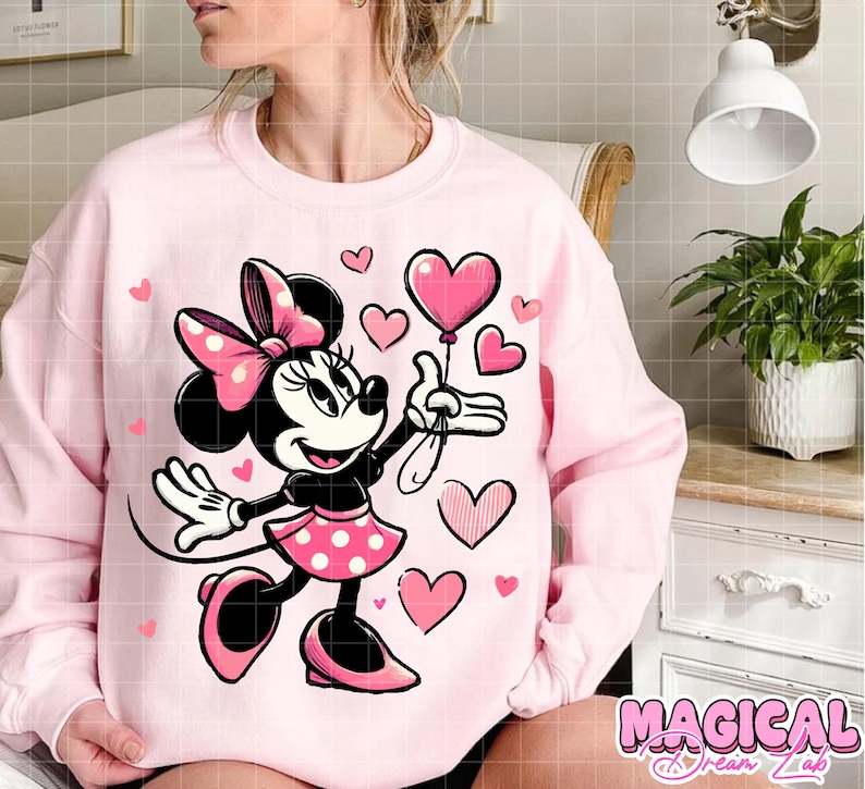 Puede incluir: Sudadera rosa claro con un dise&ntilde;o de Minnie Mouse sosteniendo un globo en forma de coraz&oacute;n. Minnie Mouse lleva una falda y un lazo de lunares rosas. Hay corazones rosas dispersos alrededor del dise&ntilde;o. El texto "MAGICAL Dream Lab" est&aacute; en la parte inferior.