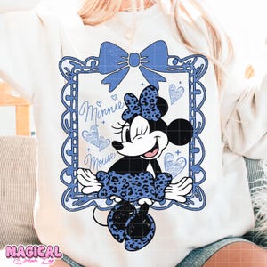May include: White sweatshirt featuring a Minnie Mouse graphic in a blue frame with a bow and hearts. The Minnie Mouse design includes a blue leopard print bow and dress, with the words "Minnie Mouse" in cursive.