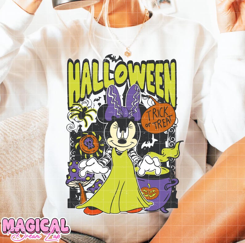 Może przedstawiać: Biała bluza z nadrukiem na Halloween przedstawiającym Minnie Mouse przebraną za potwora Frankensteina. Projekt zawiera zielony napis "HALLOWEEN", kocioł i frazę "Trick or Treat".