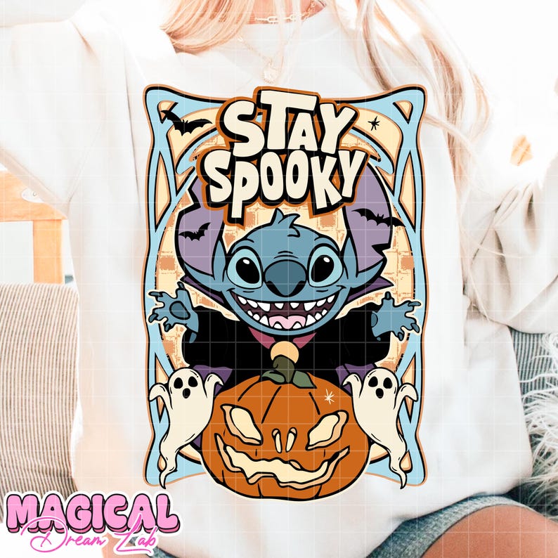 May include: White sweatshirt featuring a Halloween-themed graphic. The design includes a blue cartoon character with the text "Stay Spooky", bats, ghosts, and a jack-o'-lantern. The sweatshirt has a crew neck and long sleeves.