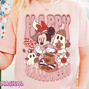 K&ouml;nnte beinhalten: Hellrosa T-Shirt mit einem Cartoon-Motiv von Minnie Mouse mit Hexenhut, die eine Trick-or-Treat-Tasche h&auml;lt, und den Worten "Happy Halloween". Das Design umfasst Geister, K&uuml;rbisse und Herbstbl&auml;tter.