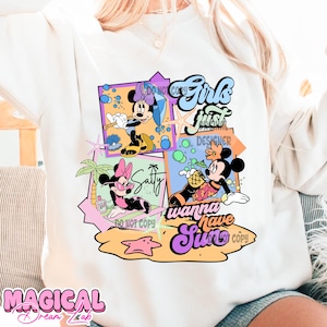 May include: A white sweatshirt with a colorful graphic design featuring Mickey Mouse and Minnie Mouse characters. The design includes the text "Girls just wanna have sun" and a beach scene with palm trees, a starfish, and a pineapple.