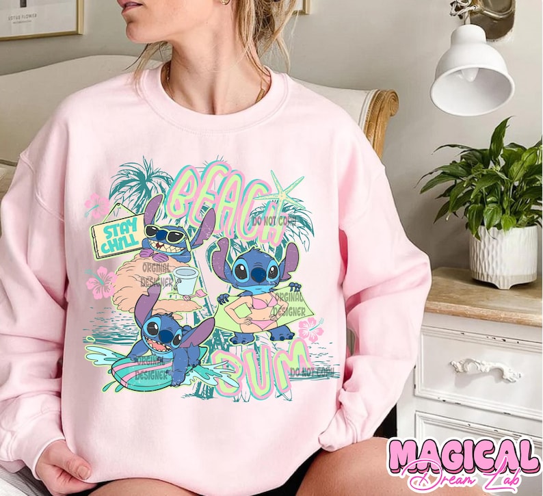 May include: Pink sweatshirt featuring a graphic of Stitch from Lilo & Stitch enjoying the beach. The design includes the words "BEACH SUM" and "STAY CHILL". Stitch is depicted surfing, drinking, and sunbathing. The words "ORIGINAL DESIGNER" are also present.
