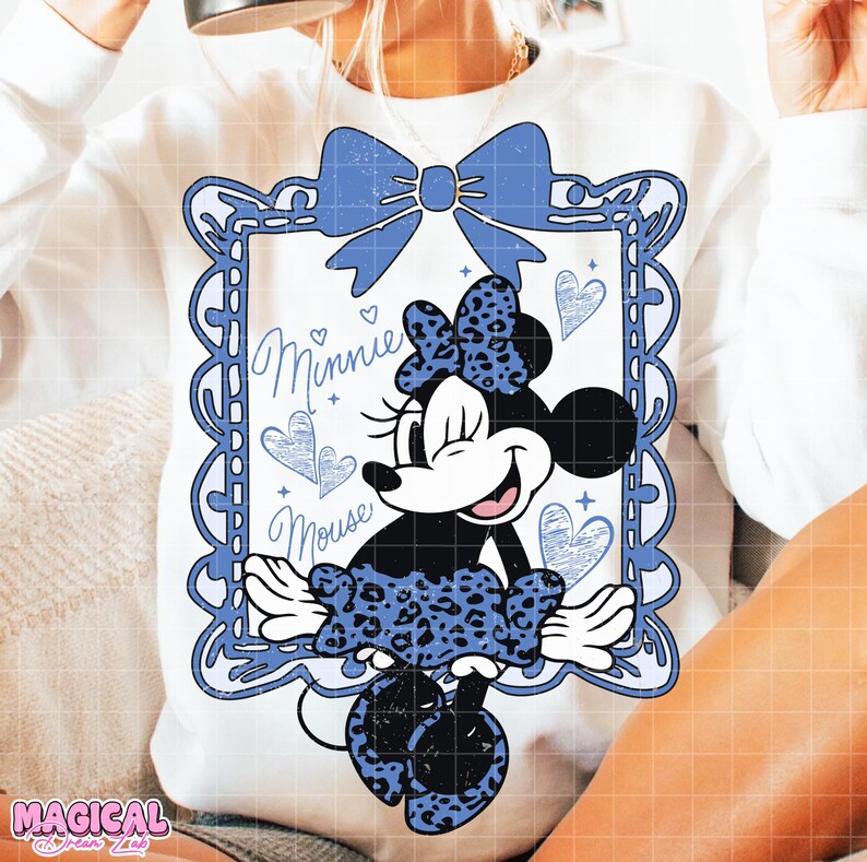 May include: White sweatshirt featuring a blue framed Minnie Mouse graphic. The Minnie Mouse design includes a blue bow, a leopard print dress, and the words "Minnie Mouse". The design also includes blue hearts.