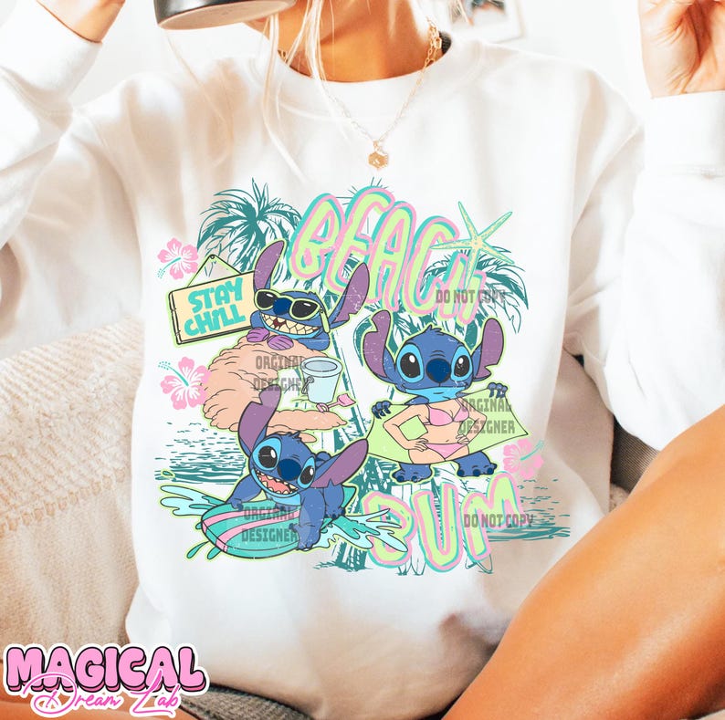 May include: White sweatshirt featuring a colorful graphic of the character Stitch at the beach. The design includes the words "BEACH SUN" and "STAY CHILL", along with tropical elements like palm trees and flowers. The words "ORIGINAL DESIGNER" are also visible.