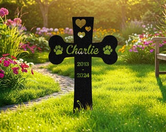 Op de afbeelding: Zwart metalen dierenherdenkingskruis met een botvorm en potafdrukken. Het kruis heeft de naam "Charlie" en de data "2013 - 2024" erop gegraveerd. Het kruis staat in een grasveld met een pad ernaartoe.