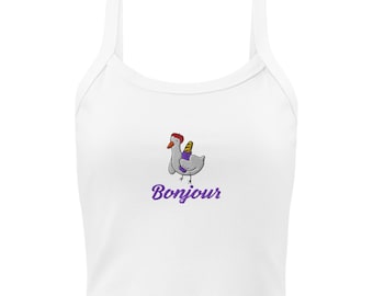 Puede incluir: Top corto blanco con un dibujo de un pollo de dibujos animados con boina roja y baguette. La palabra "Bonjour" está escrita en púrpura debajo del pollo. El top tiene cuello redondo y tirantes finos.
