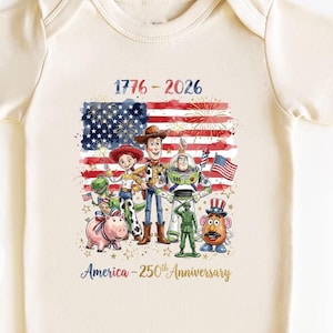 May include: A cream-colored baby bodysuit featuring a graphic print of Toy Story characters in front of an American flag. The text reads 1776-2026 and America-250th Anniversary. The design includes fireworks, stars, and patriotic colors.