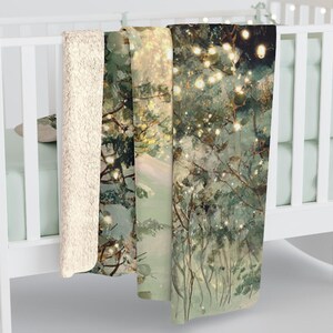 May include: A cozy blanket with a forest scene design. The blanket features a soft, cream-colored sherpa lining and a printed top with a winter forest scene with twinkling lights. The blanket is folded over a white crib.