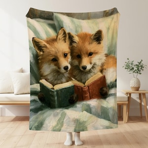 May include: A soft throw blanket featuring an oil painting style illustration of two red foxes sitting side by side on a light green and white striped surface. Each fox is holding an open book, one with a green cover and one with a brown cover.