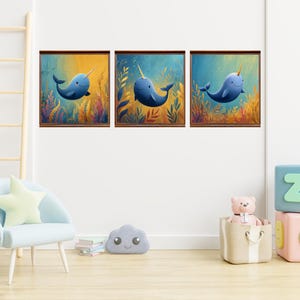 May include: A set of three square wall art prints featuring blue narwhals swimming among colorful underwater seaweed and coral. Each print is framed in a dark wood border, showcasing a whimsical aquatic scene with golden light rays.