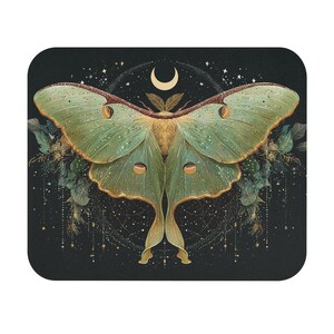 May include: A square, black mousepad featuring a detailed illustration of a Luna moth. The moth has green and gold wings with a crescent moon and stars in the background. Decorative foliage and sparkling accents surround the moth.