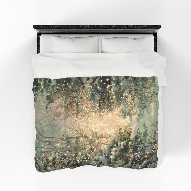 May include: A duvet cover featuring a winter forest scene with snow-covered trees and twinkling lights. The design has a soft, dreamy quality with a palette of muted greens, whites, and golden highlights. The bedding is set on a black bed frame with white pillows.