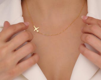 Op de afbeelding: Een gouden ketting met een klein vliegtuigje als hanger. De ketting is delicaat en simpel, waardoor het een perfect cadeau is voor een reiziger of iemand die van vliegen houdt.