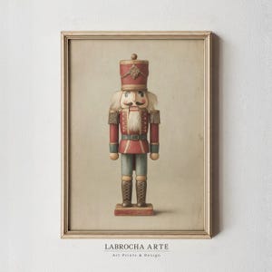 May include: A framed art print featuring a nutcracker illustration. The nutcracker wears a red uniform with gold accents, a tall hat, and has a white beard and mustache. The background is a neutral beige tone. The text LABROCHA ARTE appears below.