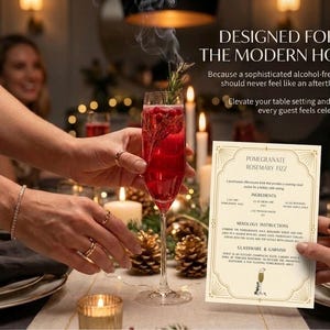 May include: A glass of red cocktail, garnished with rosemary, is held at a table setting. A recipe card for Pomegranate Rosemary Fizz is visible. The text reads "Designed for the Modern Host."