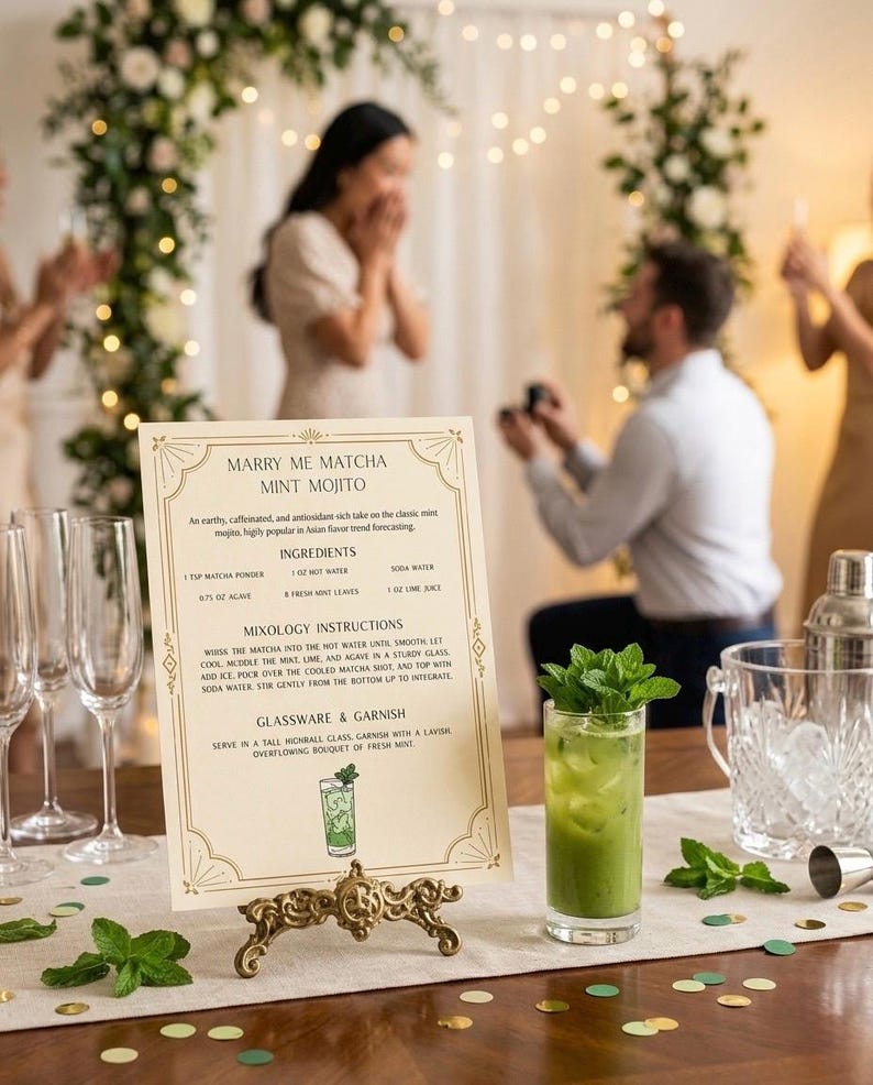 May include: A recipe card for a "Marry Me Matcha Mint Mojito" cocktail, displayed on a decorative stand. A green cocktail in a glass is visible. The card details ingredients and instructions. The background shows a proposal scene.