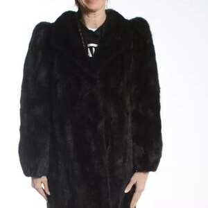 May include: A long black fur coat with a collar and long sleeves.