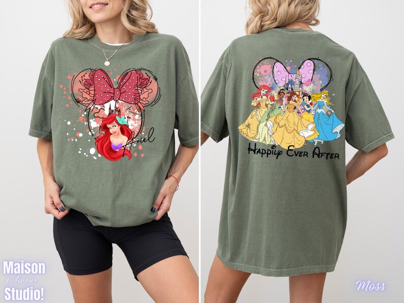 May include: Olive green t-shirt featuring a Minnie Mouse design with Ariel and the word "Ariel" on the front. The back of the shirt displays Disney princesses and the phrase "Happily Ever After".