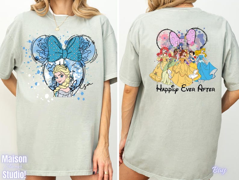 Pode incluir: Camiseta verde claro com um desenho frontal de Elsa de Frozen dentro de um contorno de orelha do Mickey, um la&ccedil;o azul e o nome "Elsa". A parte de tr&aacute;s mostra princesas da Disney com o texto "Happily Ever After".