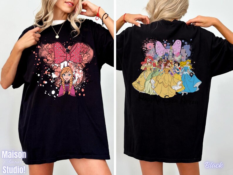 May include: Black t-shirt featuring a Minnie Mouse-inspired design with Anna from Frozen on the front. The back of the shirt displays Disney princesses. The shirt has a crew neck and short sleeves. The text "Maison Studio!" is visible on the front.