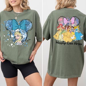 Pode incluir: Camiseta verde oliva com um desenho animado de Elsa com um la&ccedil;o azul e o nome "Elsa". A parte de tr&aacute;s da camisa mostra princesas da Disney com o texto "Happily Ever After".