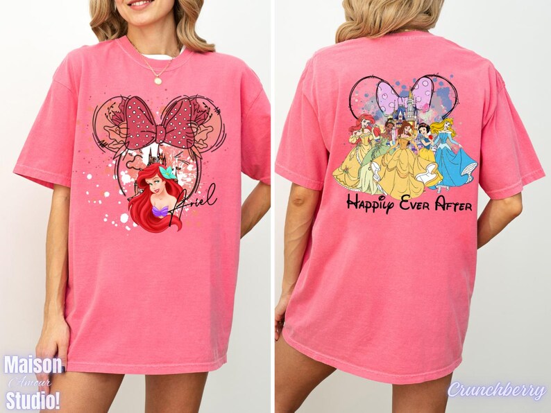 May include: A pink t-shirt featuring a Minnie Mouse design with Ariel from The Little Mermaid. The front of the shirt has Ariel's image and the name "Ariel". The back of the shirt features Disney princesses and the words "Happily Ever After".