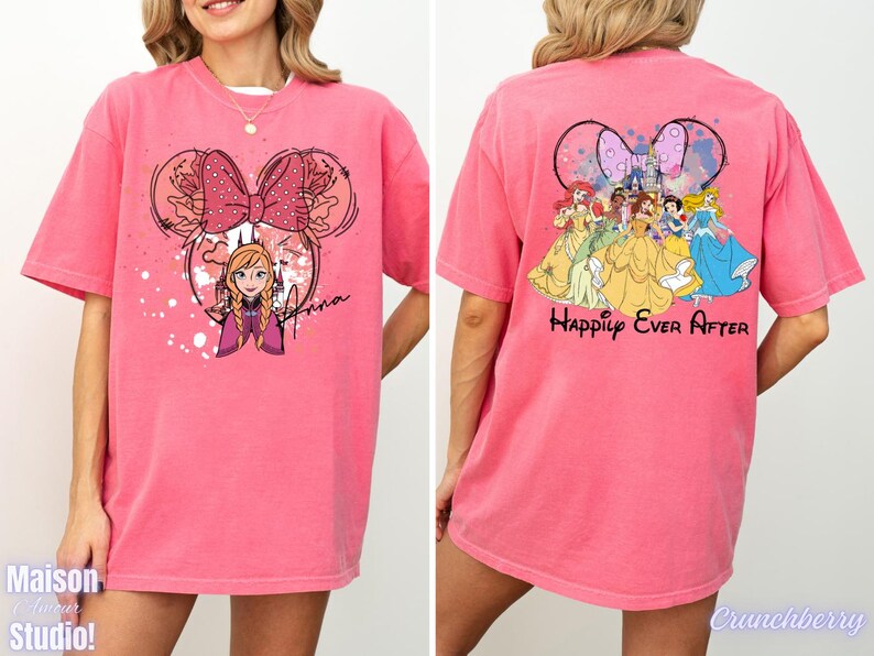 May include: Pink t-shirt featuring a Minnie Mouse-inspired design with Anna from Frozen on the front and a group of Disney princesses with the words "Happily Ever After" on the back. The shirt has short sleeves.