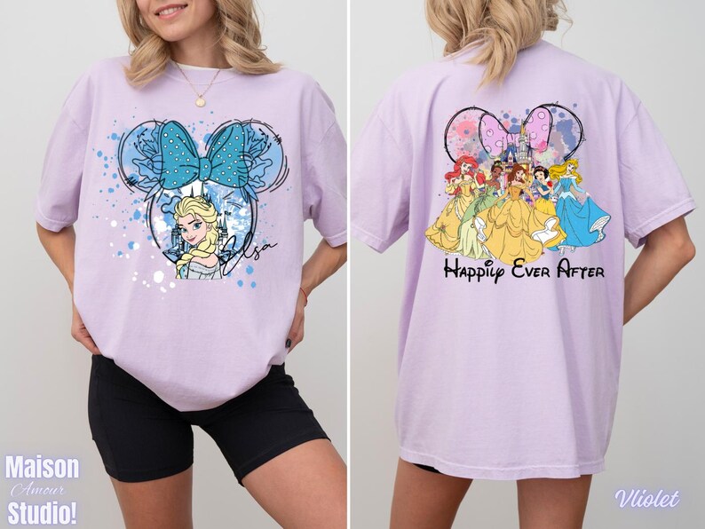 Pode incluir: Uma camiseta lil&aacute;s clara com um design inspirado na Minnie Mouse, apresentando Elsa de Frozen, um la&ccedil;o azul e o nome "Elsa". A parte de tr&aacute;s da camiseta mostra princesas da Disney e o texto "Happily Ever After".