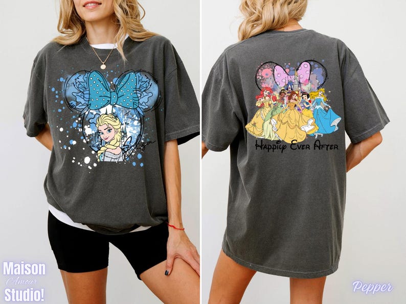 Pode incluir: Camiseta cinza escuro com um design da Minnie Mouse com Elsa de Frozen e um la&ccedil;o azul na frente. A parte de tr&aacute;s da camisa mostra princesas da Disney com o texto "Happily Ever After".