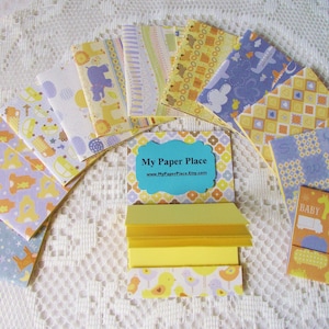 May include: A set of 10 mini notebooks with various yellow and blue patterned covers. The notebooks are arranged in a semi-circle with a business card in the center that reads "My Paper Place".