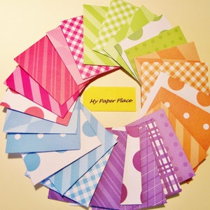 May include: A collection of 15 colorful patterned paper squares in a fan shape. The papers feature stripes, polka dots, gingham, and geometric patterns in shades of pink, blue, green, orange, and purple. The text "My Paper Place" is written on a yellow note in the center of the fan.
