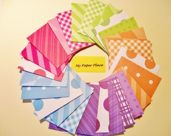 May include: A collection of 15 colorful patterned paper squares in a fan shape. The papers feature stripes, polka dots, gingham, and geometric patterns in shades of pink, blue, green, orange, and purple. The text "My Paper Place" is written on a yellow note in the center of the fan.
