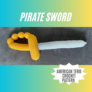 May include: Crocheted pirate sword with a yellow handle and a light blue blade. The text "PIRATE SWORD" is displayed above the sword. The text "AMERICAN TERM CROCHET PATTERN" is displayed below the sword.