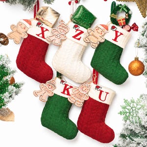 May include: Five cable-knit Christmas stockings in red, white, and green. Each stocking features a white cuff with a large embroidered red letter and a wooden gingerbread person ornament attached. The letters displayed are X, Z, Y, K, and U.