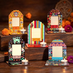 May include: Five wooden picture frames with arched tops, each featuring colorful patterns, sugar skull motifs, or floral designs. Each frame includes a small base with a lit tea light candle. The frames display various vibrant colors and intricate graphic prints.