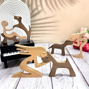 以下が含まれることがあります： 木製の置物5個セット。人々や犬の姿が描かれています。置物はシンプルでスタイリッシュなデザインで、自然な木の色合いで塗装されています。置物は白い木製の台の上に置かれています。